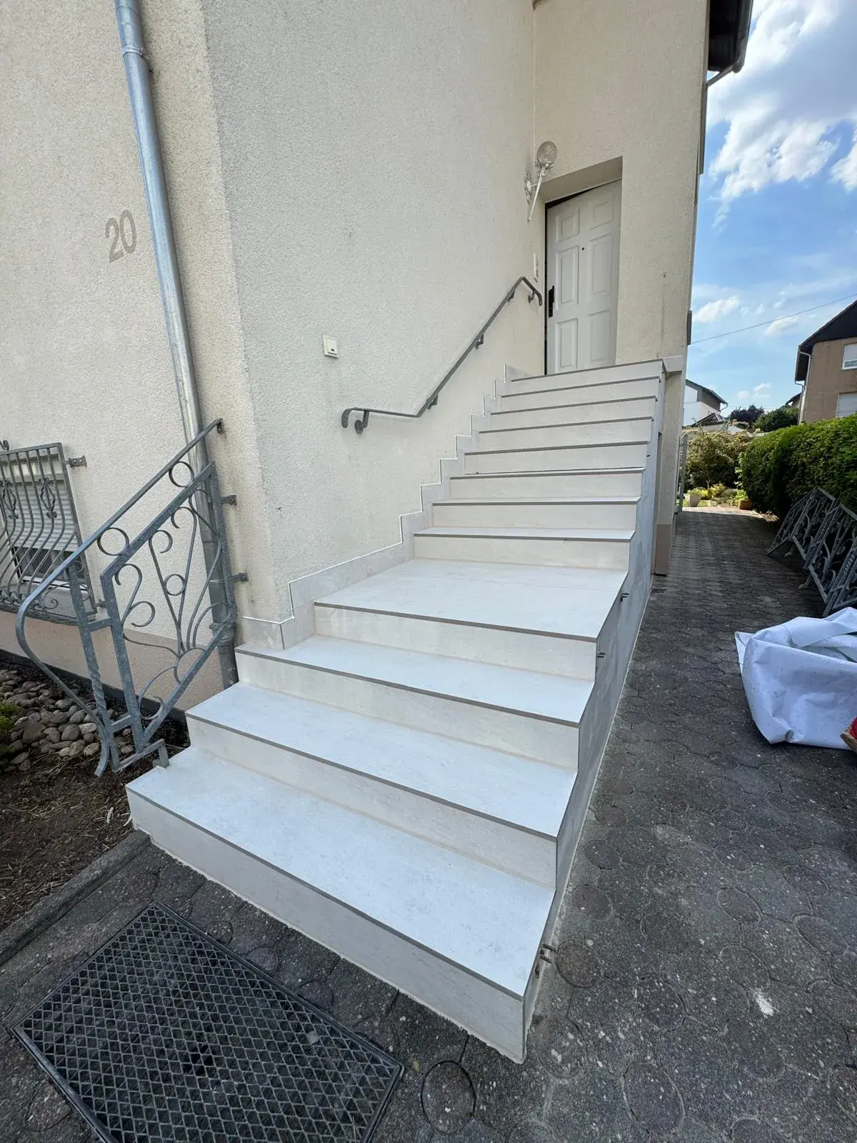Außentreppe mit hell gefliesten Stufen, Metallkantenprofilen und einem Podest vor der Haustür